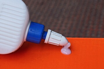 one white plastic tube with a drop of glue on a red paper