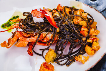 Squid ink tagliolini with lobster on white plate