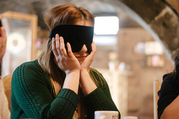 Girl with eyes covered with black fabric ribbon during playing a game