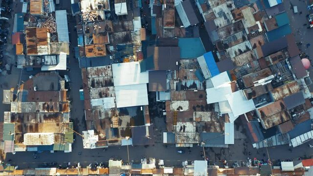 Aerial top down view of a bazaar in a slum with people between the rows