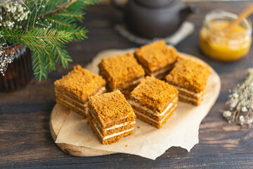 Layer Honey sliced Cake with pastry cream filling on wooden cutting board, dark wooden table near window. Close up view, copy space. Organic homemade dessert.