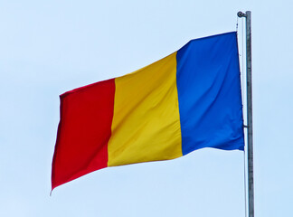 Bandera de Rumanía ondeando al viento con un cielo azul de fondo.