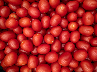 A background of a large number of small red tomatoes. Background from vegetables on a shop window. Harvesting tomatoes.