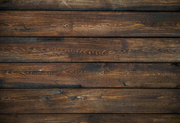 A background of dark wood planks tightly adjacent to each other. Wooden boards with a clearly visible wood texture.