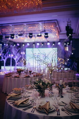 Wedding table setting and decoration. Cutlery on the table. Floral decorations in the banquet hall. Blue background.
