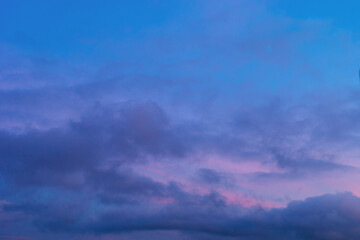 Naklejka na ściany i meble Background of mystery purple and pink clouds on blue sky at evening after sunset. Telephoto zoom photo shot