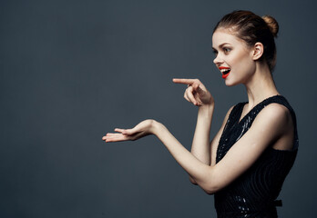 Obraz premium Woman shows emotions with hands to the sides on gray background Copy Space