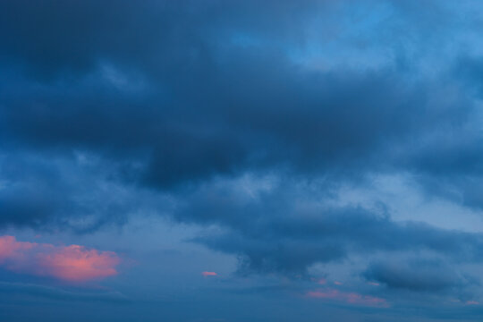 Background of mystery cumulus blue and pink clouds on a blue sky at evening after sunset. Telephoto zoom photo shot.