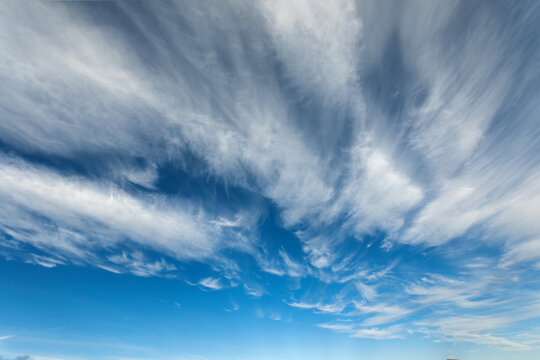 Beautiful blue sky background at daylight with white streched spindrift clouds. Wide angle photo shot at 17 mm