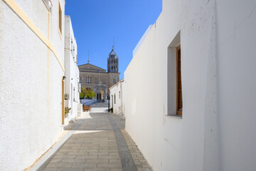 Fototapeta na wymiar Narrow street in Lefkes village on Paros Island. Church of Agia Triada in background. Greece