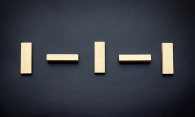 The concept of social distancing. Wooden blocks of toys are placed on a black background with an interval. The view from the top.