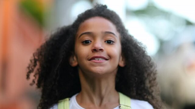 Mixed race little girl walking forward outside. Cute black female kid
