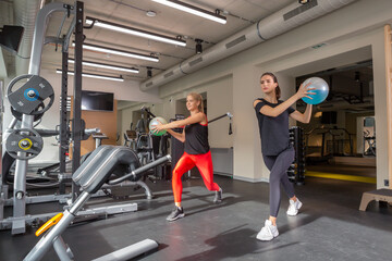 Fototapeta na wymiar Two sporty young woman exercising with the ball in the gym