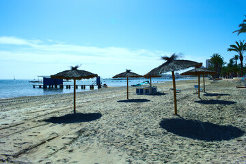 Lo Pagan beach, Mar Menor, Spain. Seaside landscape with rows of sun shad umbrellas. Landscape  aspect with copy space. 
