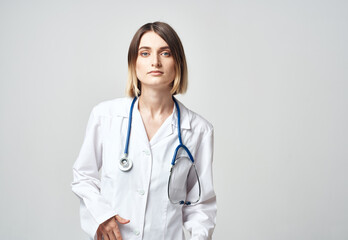 Fototapeta premium Professional doctor woman with blue stethoscope and white medical gown