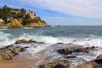 Fototapeta na wymiar Castell d'en Plajan on the Costa Brava and city beach in Lloret de Mar, Spain. Sand and sea waves.