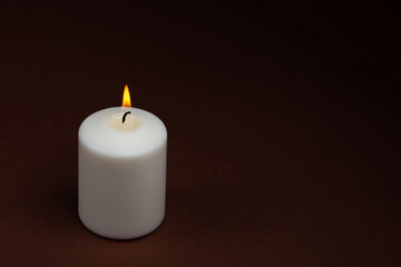 Fototapeta na wymiar One white candle flame burning on dark background with copy space for text.