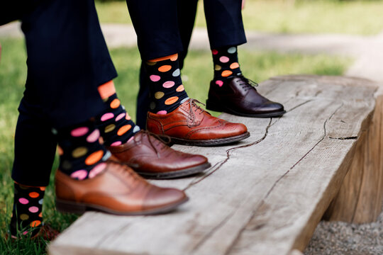 Feet of the groom and friends of the groom with funny colored socks. Men in colorful socks and black shoes. They stand in a circle. FASHION, STYLE, BEAUTY