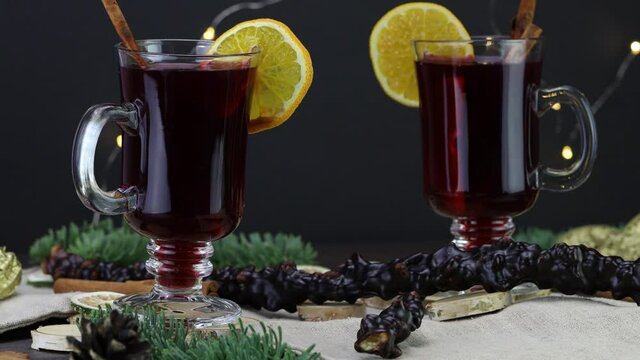 A female hand puts the Churchkhela on the table, against the background of a Mulled wine with an orange