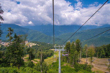 Ski lift in the mountains near the city of Sochi in summer. Scenic view with beautiful clouds over...
