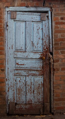 Fototapeta na wymiar Blue door with peeled paint in a brick wall