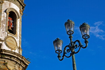 Fototapeta na wymiar Ancient light pole and baroque church, Sao Joao del Rei, Brazil
