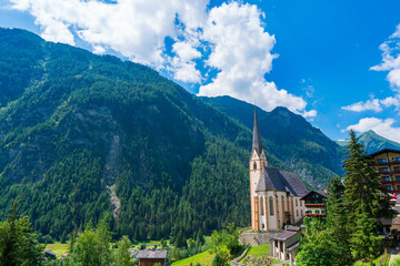 Fototapeta premium A scenic landscape photo of the Austrian municipality of Heiligenblut with St. Vincent Church in front of the Hohe Tauern mountains. Cetral Alps mountains in the background.