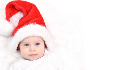 Christmas baby. Cute four month old baby in a Santa Christmas hat lying on back on white background. Copy space. Christmas and New Year Card.