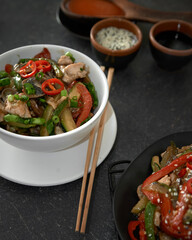  Soba noodles with chicken, hot pepper, zucchini, mushrooms, green onions on the   dark background. Selective focus. Asian food