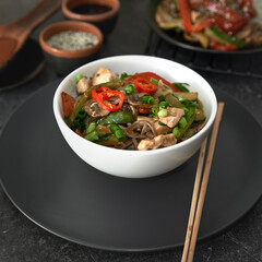  Soba noodles with chicken, hot pepper, zucchini, mushrooms, green onions on the  dark  background. Selective focus. Asian food