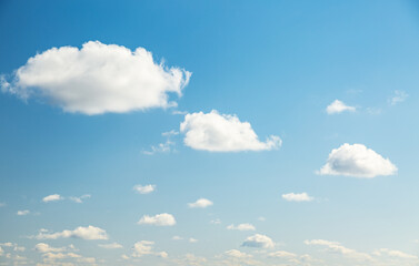 Blue sky background with white fluffy clouds in the fresh sunny day.