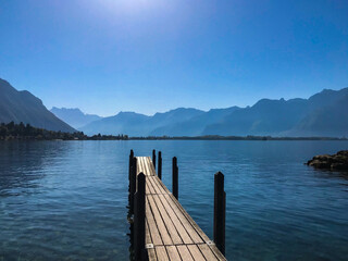 Fantastic view of lake Geneva on a Sunny day . Absolutely blue sky. Dramatic and picturesque scene with a wooden bridge. Popular tourist attraction. The location of the town of Montreux, Europe. World