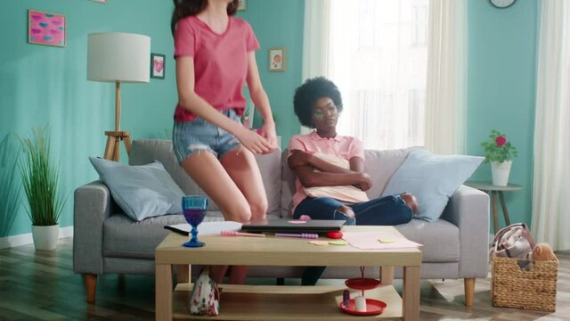 Young Afro-American woman is sitting on sofa at home, feeling sad and bored, missing her friends and family, her roommate joins her and is trying to cheer up, focusing on positivity, Slow motion.