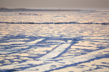 Popękana tafla zmrożonego lodu w pięknym oświetleniu zachodzącego słońca