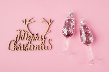 Christmas  concept. Top above overhead view photo of wine glasses with pink confetti inside and wooden handmade merry christmas sign isolated on pastel pink background