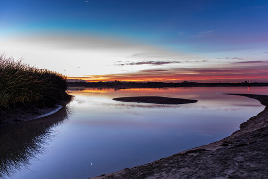Estuary water surface reflects the golden sky with sand bar island silhouetted against morning sunrise. © motionshooter