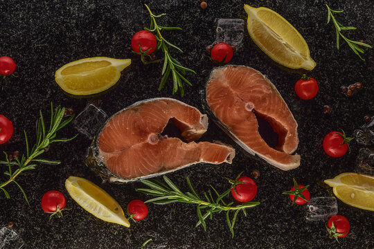 Salmon in ice with lemons on a black and wilted background, fresh headless fish