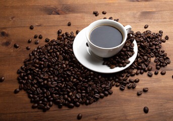 Coffee beans and cup of coffee on old wooden table.