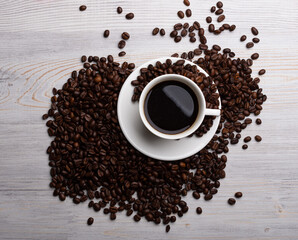 Coffee beans and cup of coffee on old wooden table.