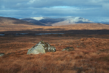 A large stone on a high-mountain plateau against a background of snowy mountain peaks. Scenic...