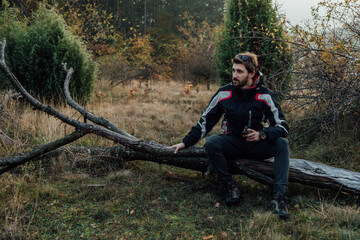 A young man uses a military compass for orientation in nature, talking on the phone, surrounded by fog.