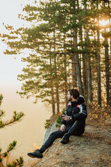 A young man uses a military compass for orientation in nature, talking on the phone, surrounded by fog.