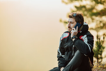 Fototapeta premium A young man uses a military compass for orientation in nature, talking on the phone, surrounded by fog.