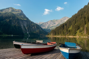 Fototapeta na wymiar Vilsalpsee, Austria: Image of rowboats on a floating platform with beautiflu mountains in the background.