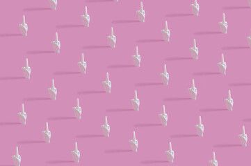 Creative pattern concept with human hands gesturing middle finger on pastel pink background. Flat lay design.