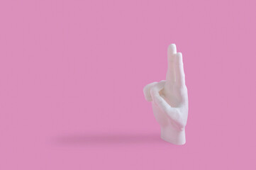 Creative concept with human hand showing two fingers up on pastel pink background. Flat lay design