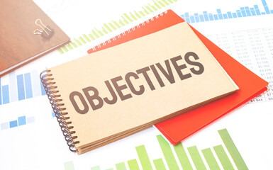 Word writing text OBJECTIVES on notepad. Business concept with red notepad and financial amounts.