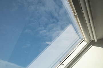 Interior view and close-up detail at closed white Tilt Window Skylights at attic and background of sunny blue sky.