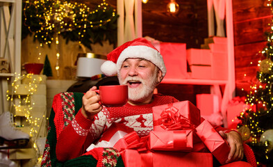 Obraz na płótnie Canvas Merry christmas. Bearded senior man Santa Claus. Santa Claus relaxing in arm chair. Delivering gifts. Winter vacation. Elderly grandpa at home. Traditions concept. Santa Claus near christmas tree