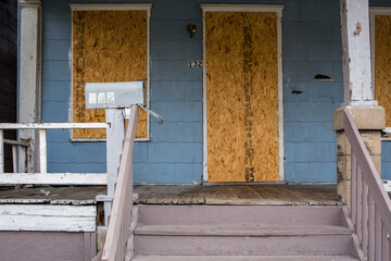 A dilapidated foreclosed home sits boarded up and empty